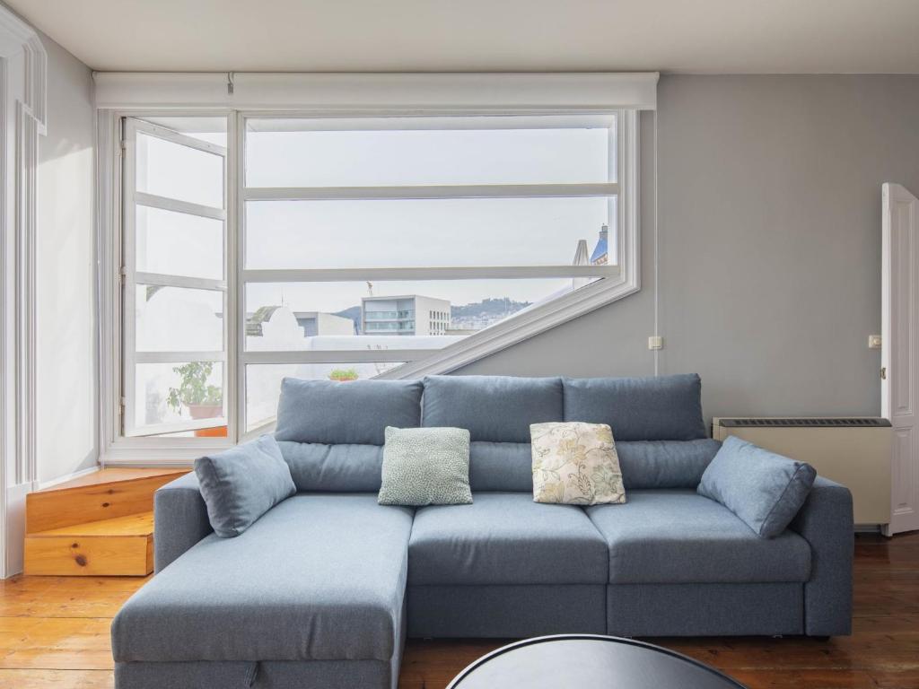 维戈Apartamento Vigo, 3 dormitorios, 7 personas - ES-210-2的客厅设有一张蓝色的沙发,配有大窗户