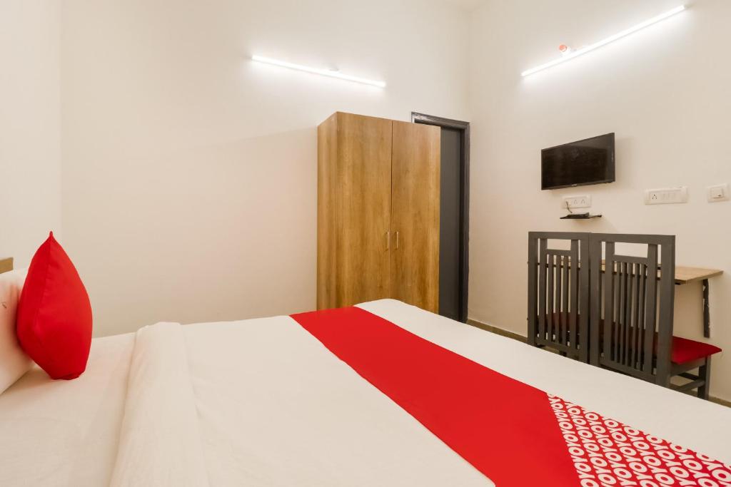 法里达巴德Perky Stay的一间卧室配有一张带红色枕头的床和一台电视。