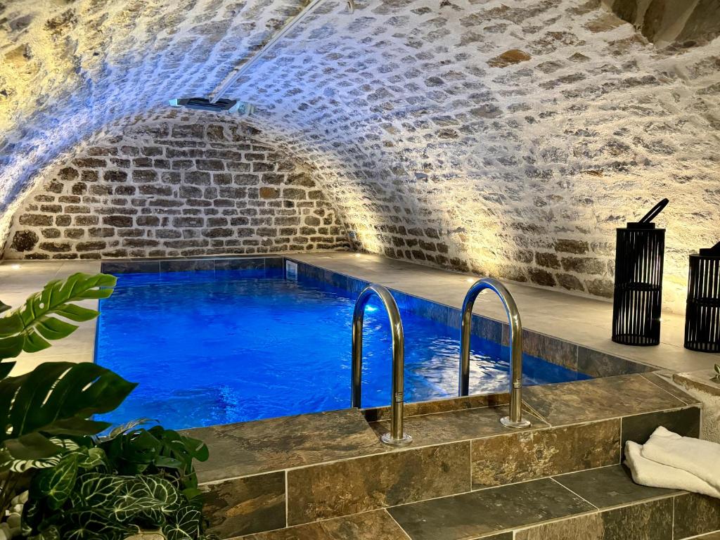 滨海布洛涅Les Suites de l'Enclos - L'Enclos de l'Evêché的蓝色水洞中的游泳池