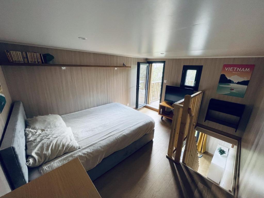 莱玛日Tiny House en lisière de forêt的一间卧室配有一张床、一张书桌和一个窗户。