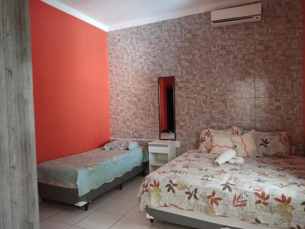 阿拉卡茹Casa confortável com piscina compartilhada的一间卧室设有两张床和砖墙