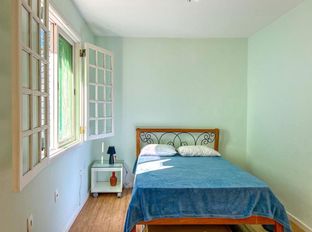 里约热内卢Otima casa com lazer completo em Sao Conrado RJ的一间卧室配有一张带蓝色毯子的床和两个窗户。