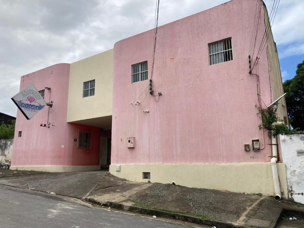 马塞约Pousada Caliente的街道边的粉红色建筑
