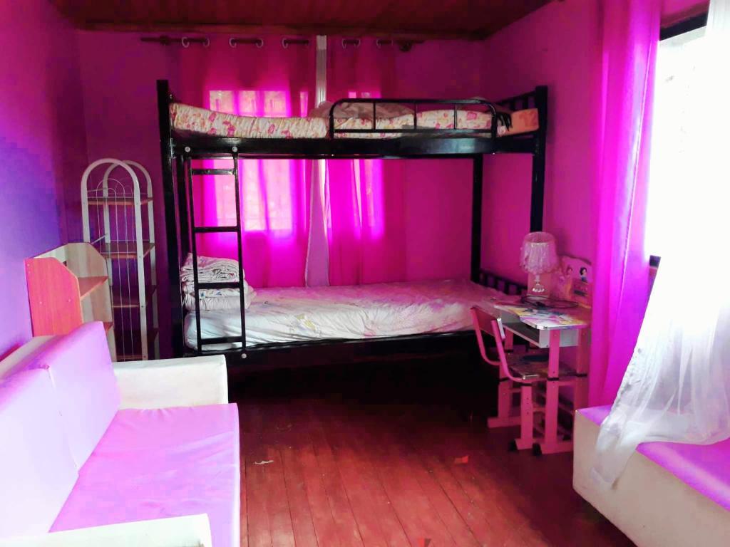 安齐拉贝Villa Caroline的粉红色的客房设有两张双层床和一张桌子