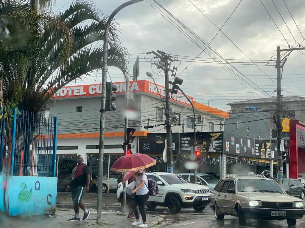 瓜鲁柳斯Hotel Cumbica的两个人在一条街道上用粉红色的伞行走
