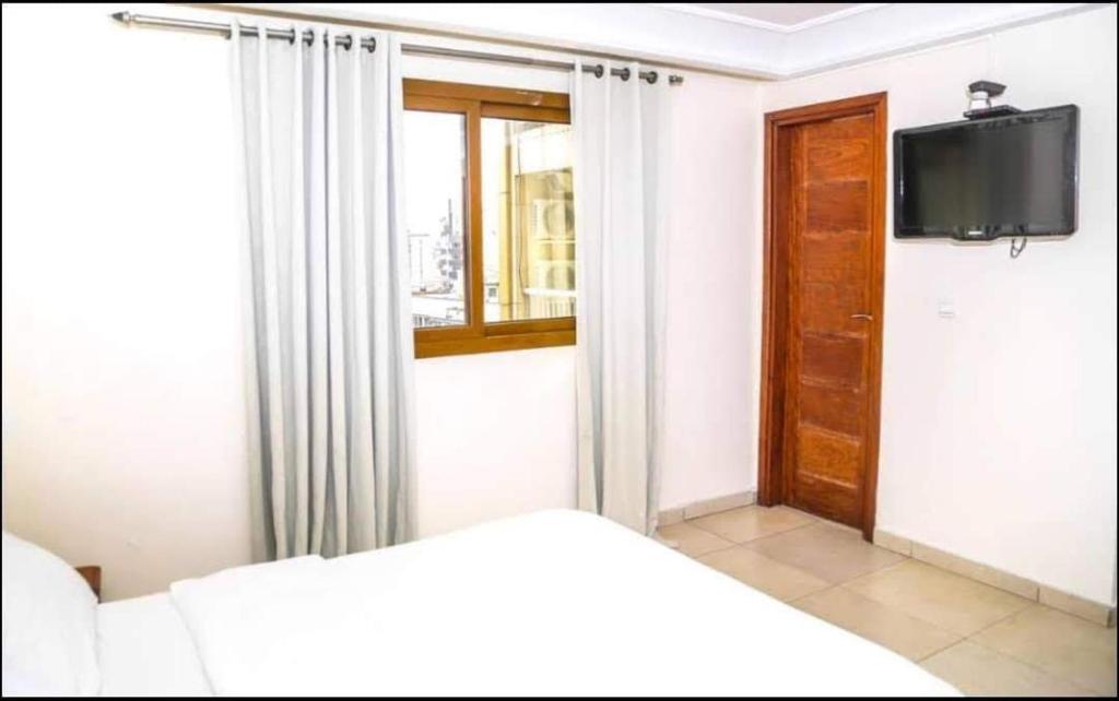杜阿拉Hannatel Rooms Liberté的一间卧室设有一张床、一台电视和一个窗口。