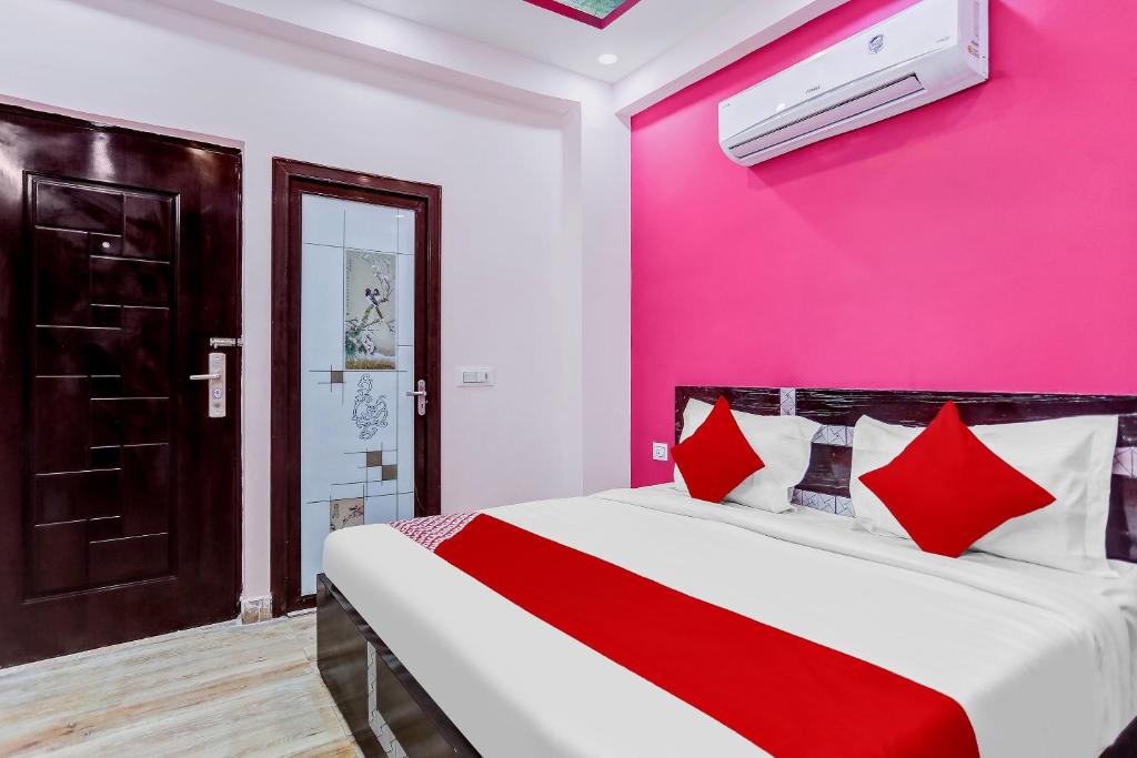 加济阿巴德Super OYO The Prima Residency的一间卧室设有粉红色的墙壁和一张带红色枕头的床。