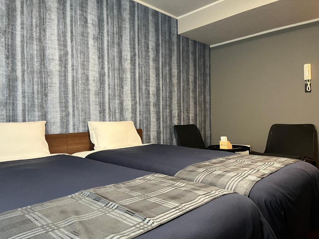 福冈机场住宿公寓式酒店的酒店客房,配有两张床和两把椅子