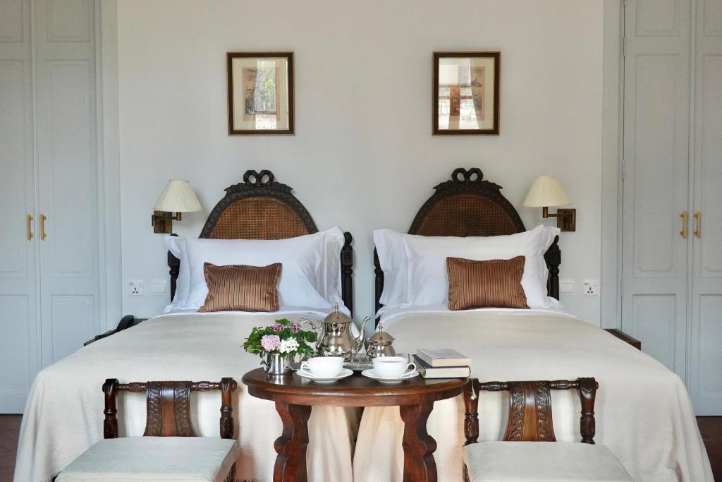 清迈Sela Chiangmai的两张带白色床单的床和一张带鲜花的桌子
