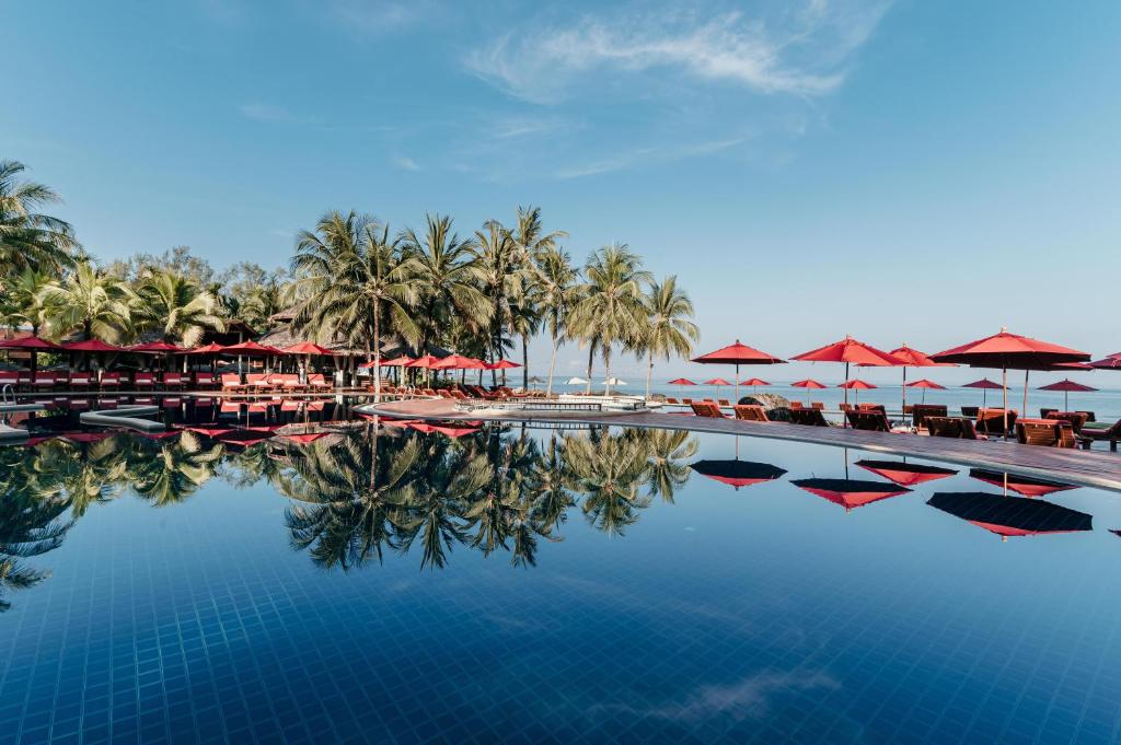 蔻立Khaolak Laguna Resort的一个带遮阳伞和椅子的游泳池以及一个度假村