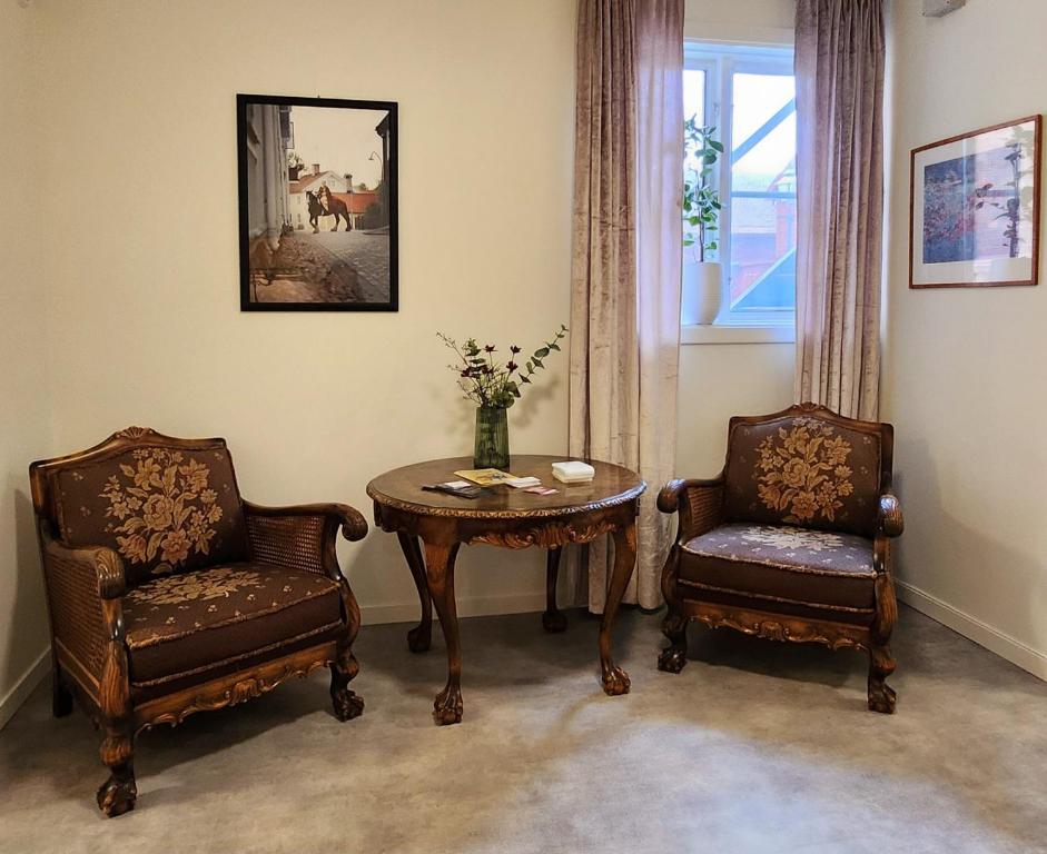 埃克舍Vandrarhemmet Garvaren gamla stan Eksjö的客厅配有两把椅子、一张桌子和一张桌子以及椅子