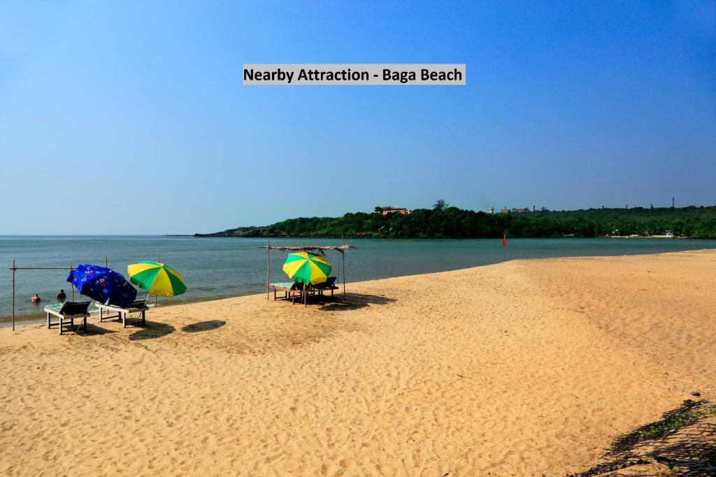巴加OYO Royal Castle Near Baga Beach的沙滩上两把带遮阳伞的沙滩椅