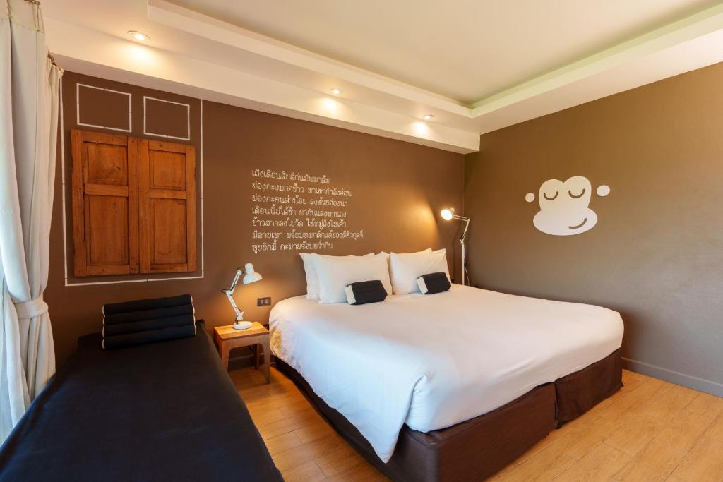 乌隆他尼Blu Monkey Brown House Udonthani的卧室配有一张大床,墙上挂着猴子标志