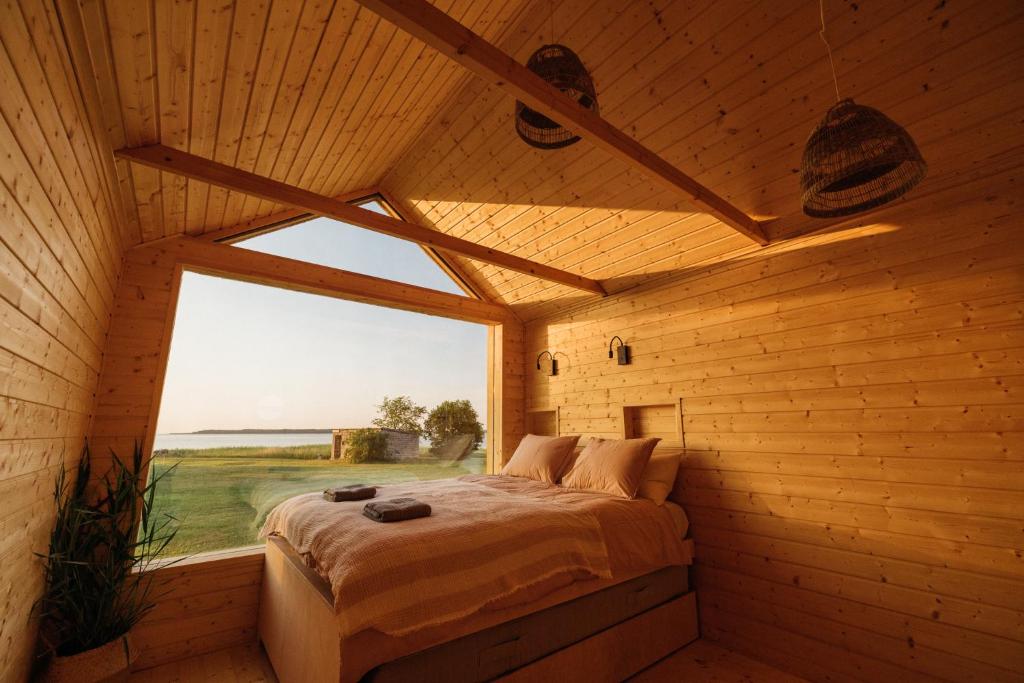 OrissaareSunset Bungalow的木制客房的一间卧室配有一张床,设有窗户