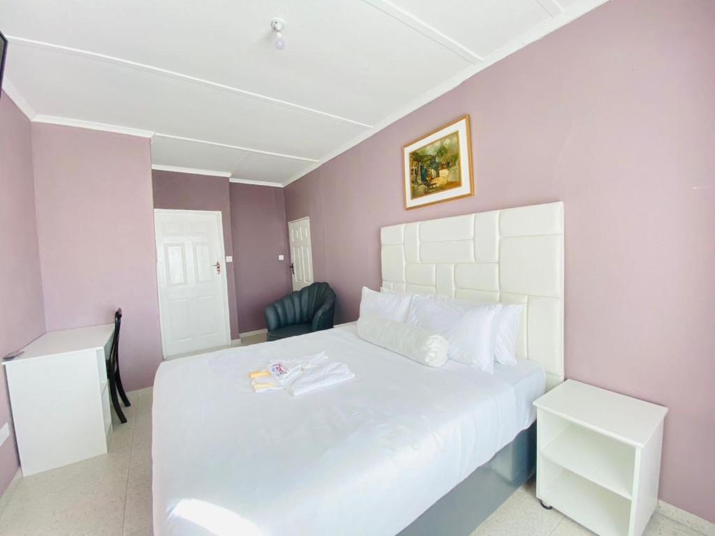 布拉瓦约Cumberland Guest Lodge的卧室配有白色的床和紫色的墙壁