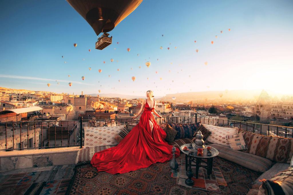 格雷梅Zara Cave Hotel的穿着红色衣服的女人站在带气球的阳台