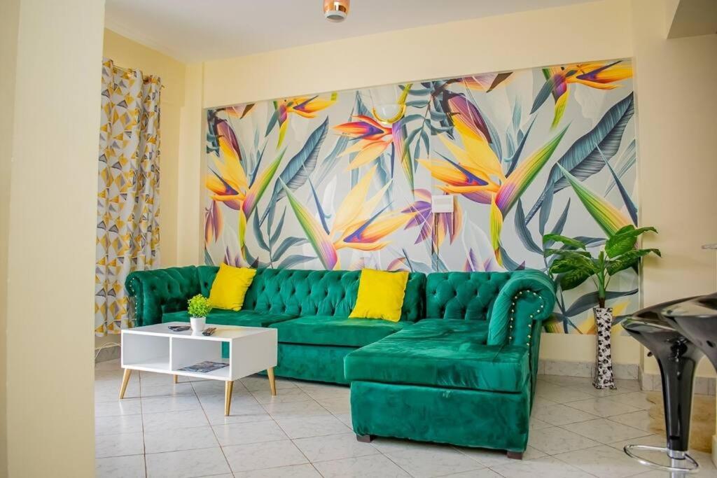 ThikaMogul's Palace (3 beds) Thika town的客厅里一张绿色的沙发,上面有绘画作品