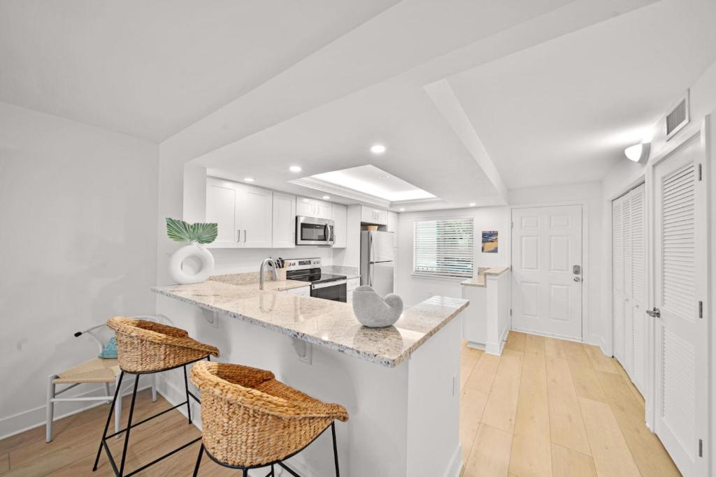 萨尼贝尔Loggerhead Cay #401的厨房配有白色橱柜和带凳子的台面