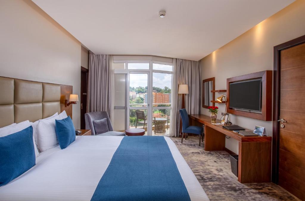 坎帕拉Golden Tulip Canaan Kampala的酒店客房,配有床和电视
