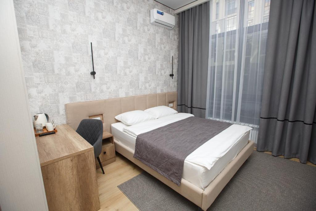 阿斯塔纳Отель Asyl的一间卧室配有一张床、一张书桌和一个窗户。