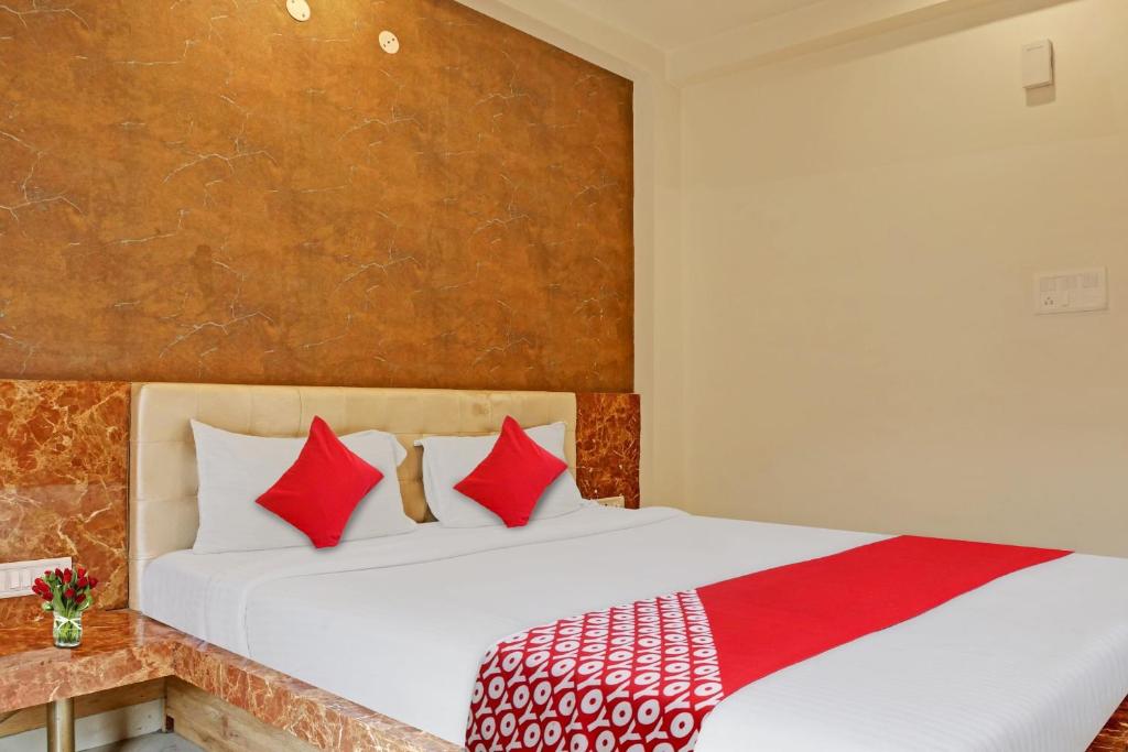 LukerganjOYO Flagship Bliss Inn的一间卧室配有一张带红色枕头的大床
