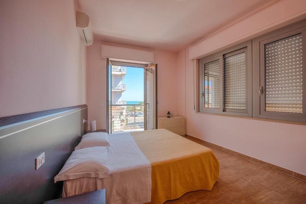 托尔托雷托Residence Palazzo Gasparroni的一间卧室设有一张床和一个大窗户