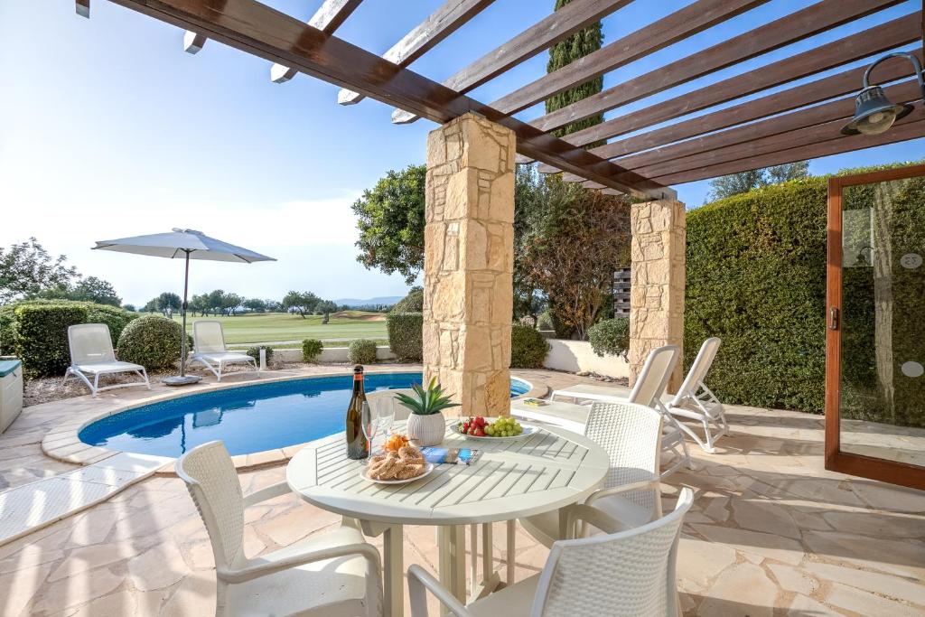 库克里亚2 bedroom Villa Kornos with private pool and golf views, Aphrodite Hills Resort的池畔露台配有桌椅
