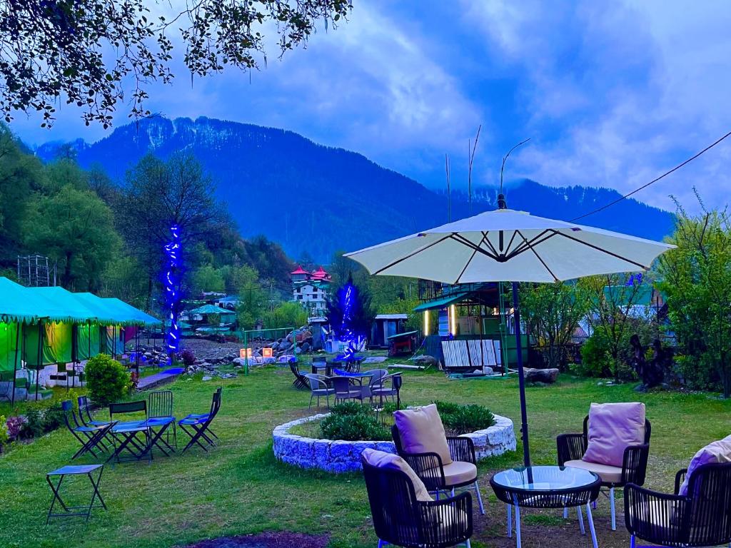 马拉里Himalayan Hill Queen Resort, Manali的一组桌椅和一把伞