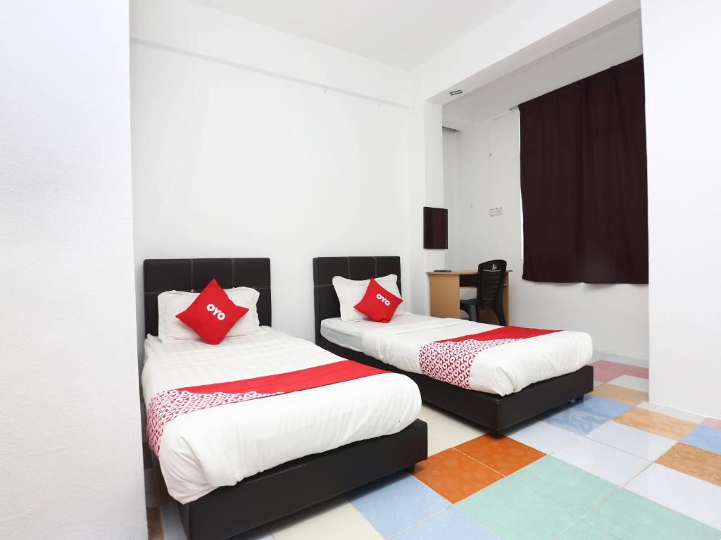 哥打巴鲁KB Rest Inn-Twin Single的客房内的两张床和红色枕头