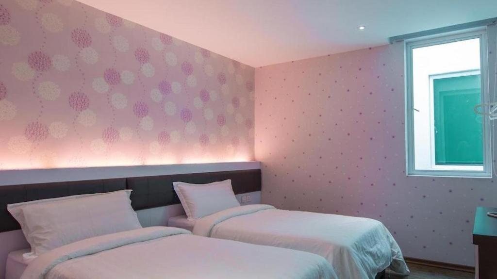 马六甲Riverfront Melaka Hotel的配有粉红色墙壁的客房内的两张床