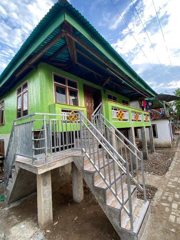KomodoDua Putri Komodo Homestay的一座绿色房子,前面有楼梯