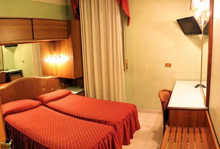 米兰维也纳酒店的一间卧室配有红色的床和一张桌子