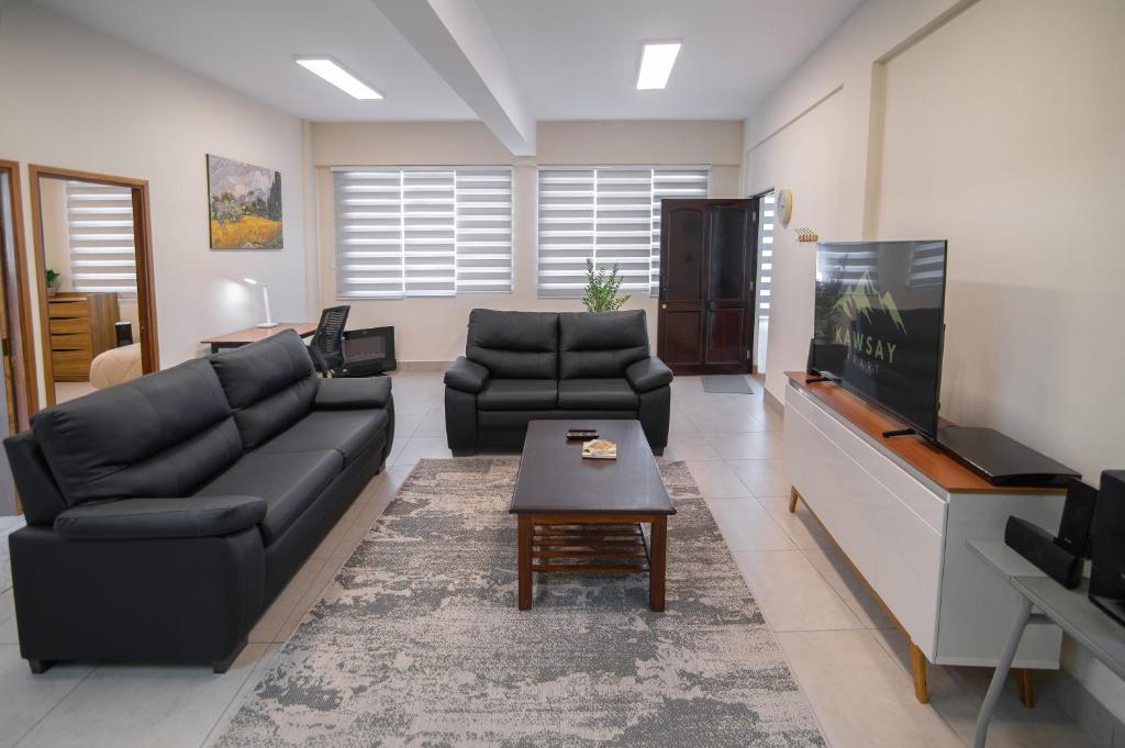 拉巴斯Kawsay Apart的客厅配有两张黑色沙发和一台电视机