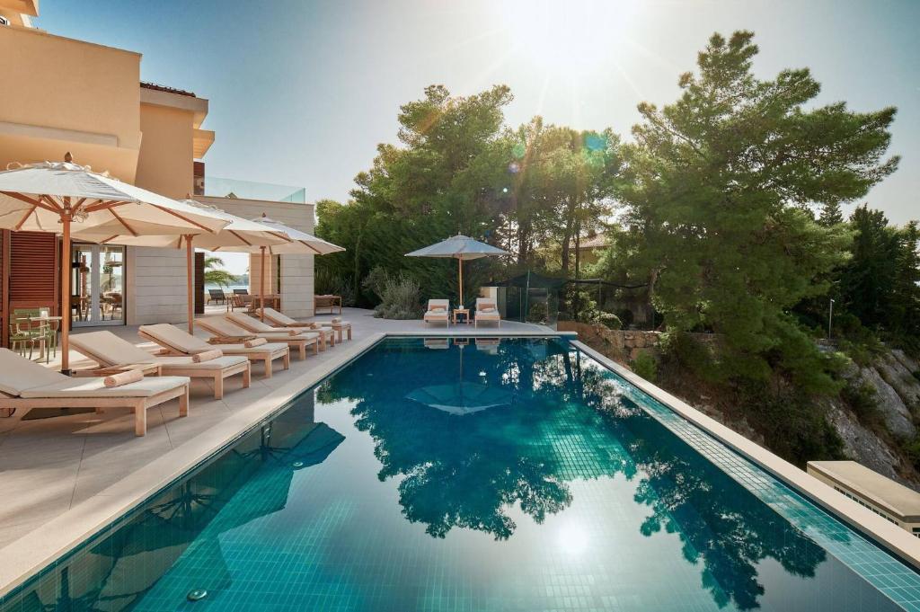 赫瓦尔Beautiful Villa Crystalsea 2 with a pool in Hvar的房屋旁的游泳池配有椅子和遮阳伞