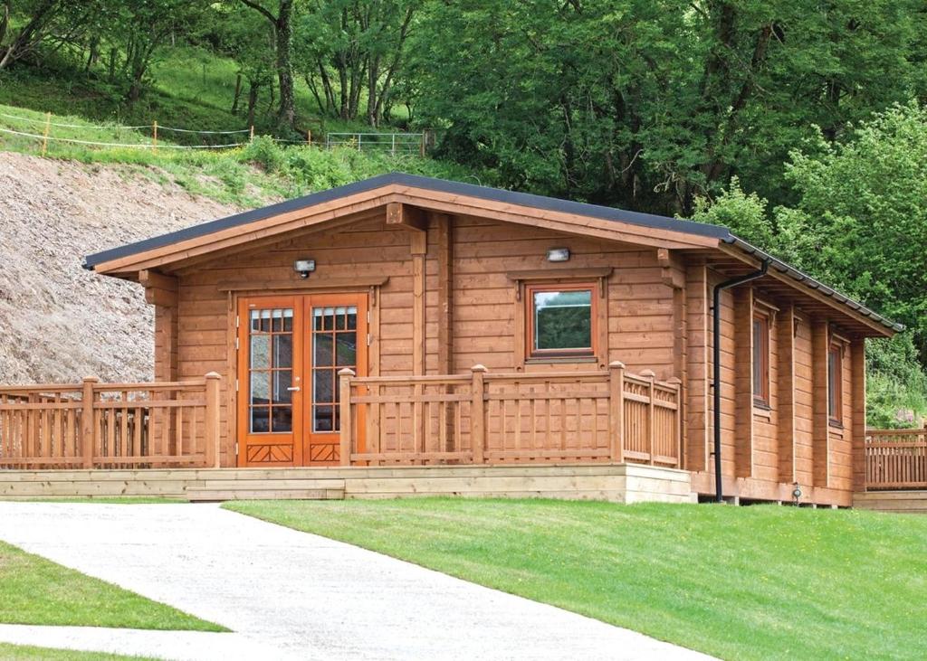 WhitestoneKingsford Farm Lodges的一间位于草坪上的门廊的小木屋