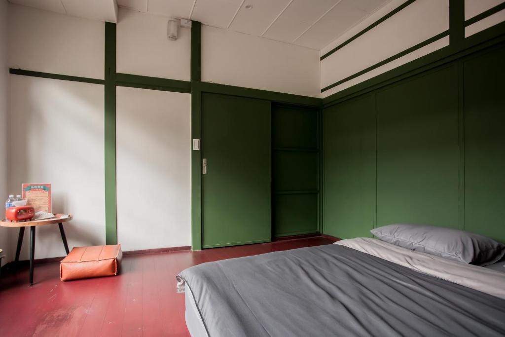高雄兴华居室的一间卧室设有绿色的墙壁、一张床和一张桌子