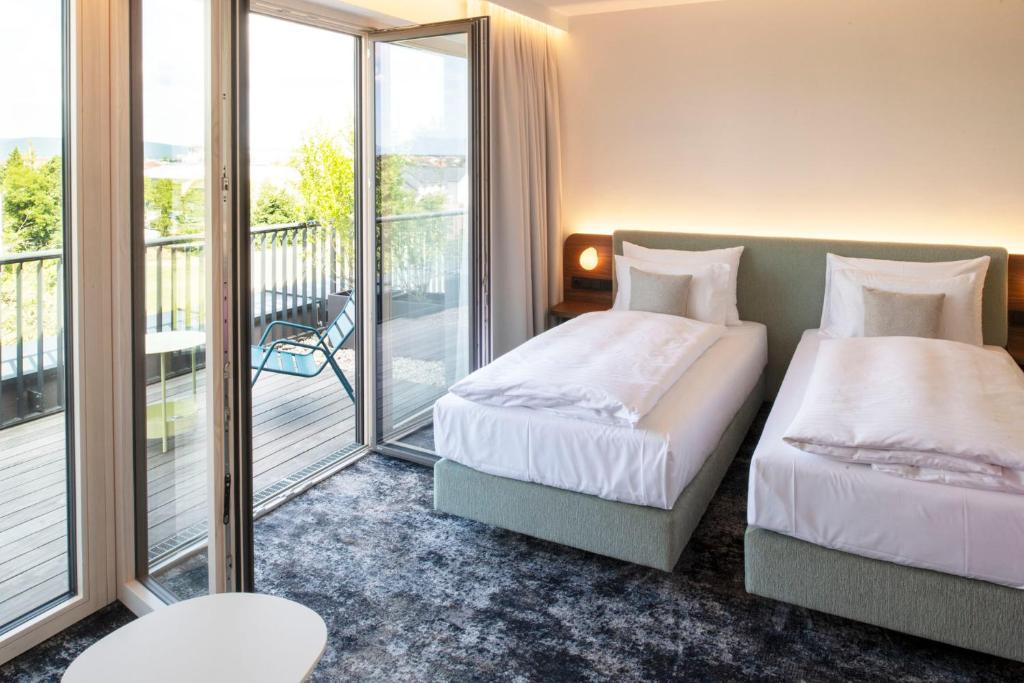 维也纳新城Hotel Le Parc的带阳台的酒店客房内的两张床