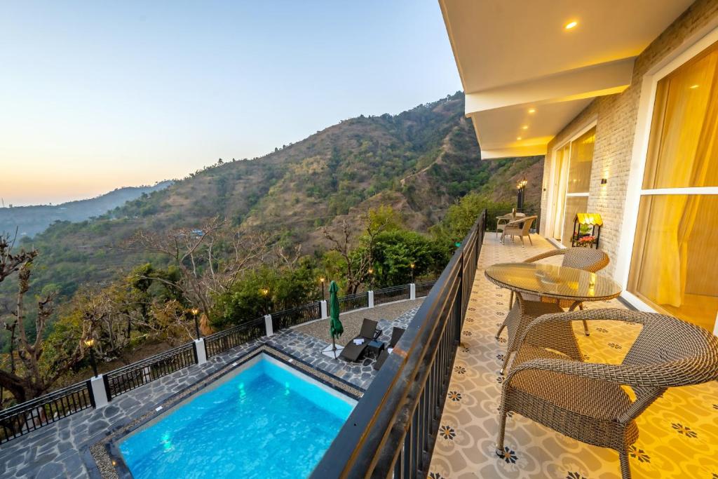 奈尼塔尔sunset villa的阳台设有游泳池和桌椅。