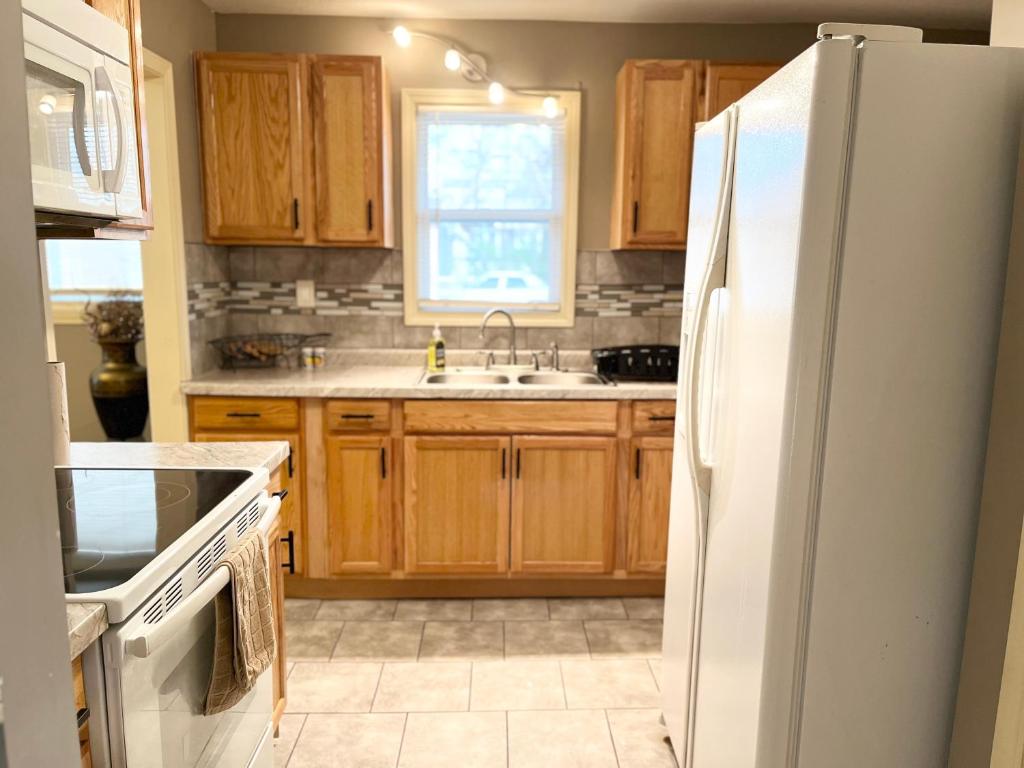 堪萨斯城The Woodland Villa的厨房配有木制橱柜和白色冰箱。