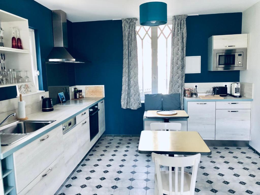 吉维尼Orpheus Lodge的厨房设有蓝色的墙壁、白色的橱柜和一张桌子