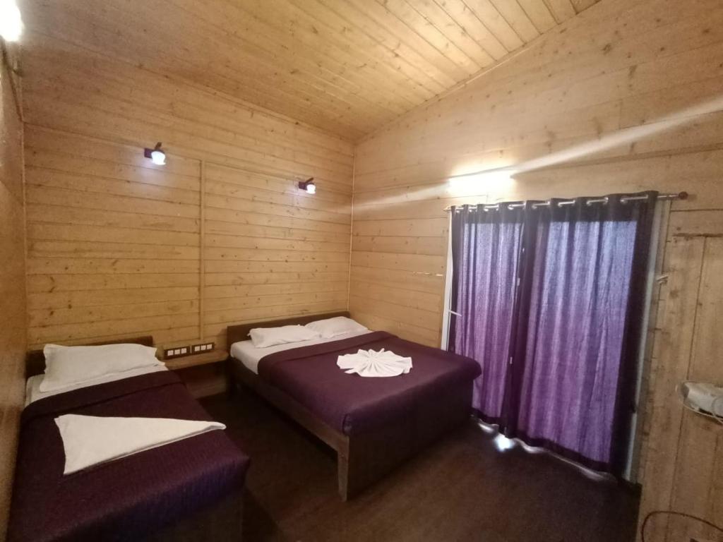 科代卡纳尔Praveen Woodhouse and Homestay Kodaikanal Vattakanal的小木屋内带两张床的房间