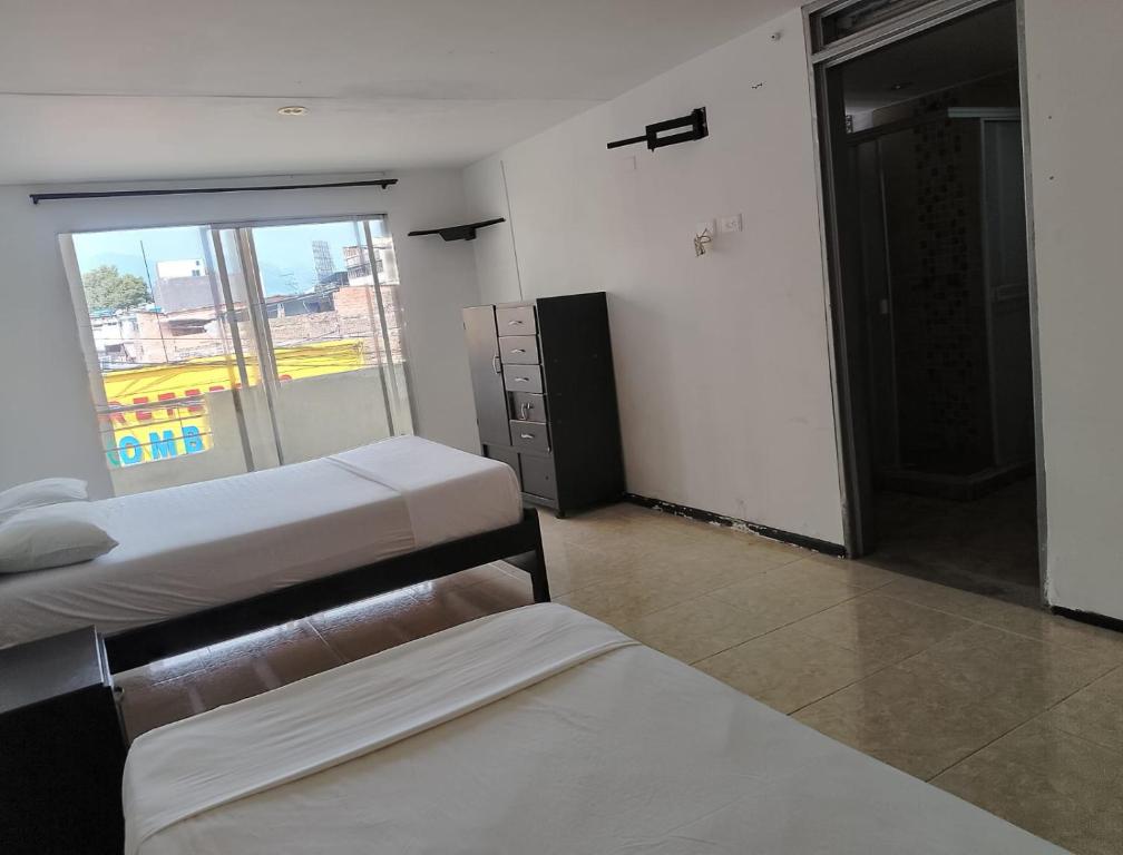 伊瓦格Hotel Bolivariano AV的一间卧室设有两张床和窗户。