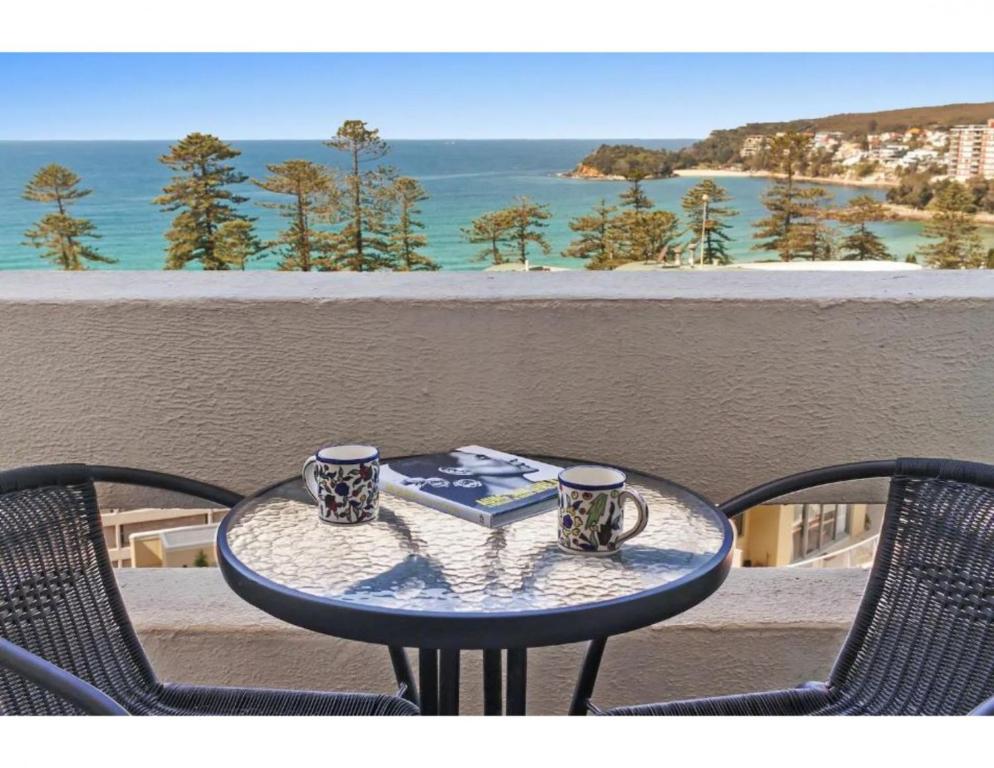 悉尼Beachside Paradise - Ocean Views, Central Position的一张桌子,上面有两杯咖啡和一本书