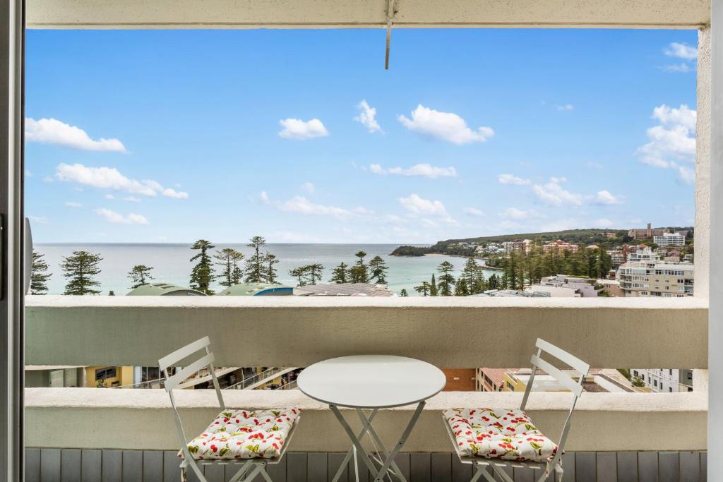 悉尼Apartment with Pool Access, a minute to the Beach的阳台配有桌椅,享有海景。