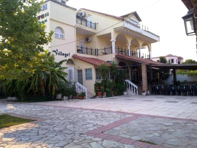 伊古迈尼察村庄酒店的一座白色的大建筑,前面设有一个庭院