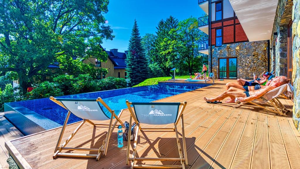 斯克拉斯卡波伦巴Apartament C3 Green Resort z Basenem, Sauną, Jacuzzi - 5D Apartments的两人躺在池畔甲板上的草坪椅上