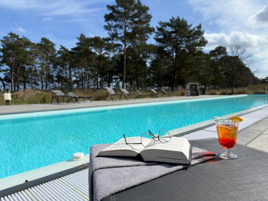 宾茨Inselloft-Rügen的游泳池旁桌子上的书和眼镜