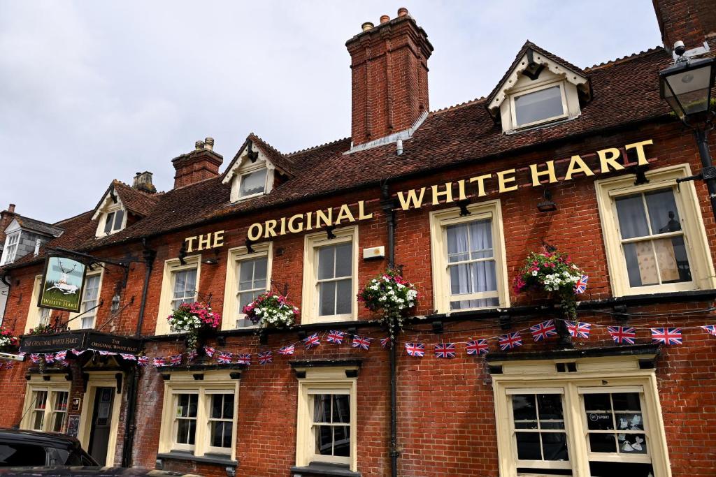 灵伍德Original White Hart, Ringwood by Marston's Inns的旧红砖建筑,带原装白色帽子