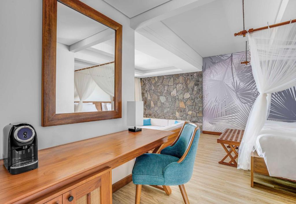 马埃岛贝拉扎尔区凯宾斯基的一间卧室配有书桌和一张带镜子的床
