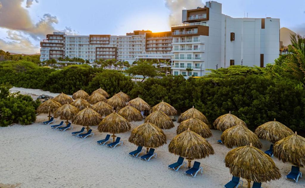 棕榈滩Embassy Suites By Hilton Aruba Beach Resort的海滩上的一把稻草遮阳伞和椅子